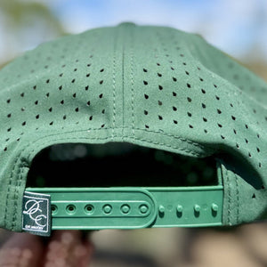 Green perforated cap with a brand logo on a blurred natural background
